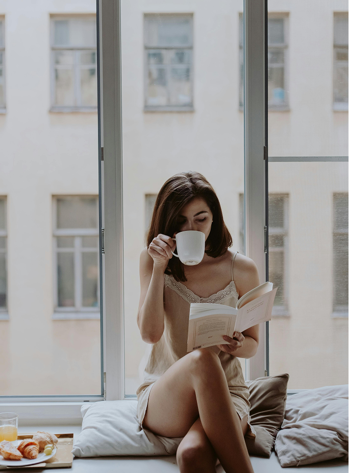 woman drinking coffee while reading a book